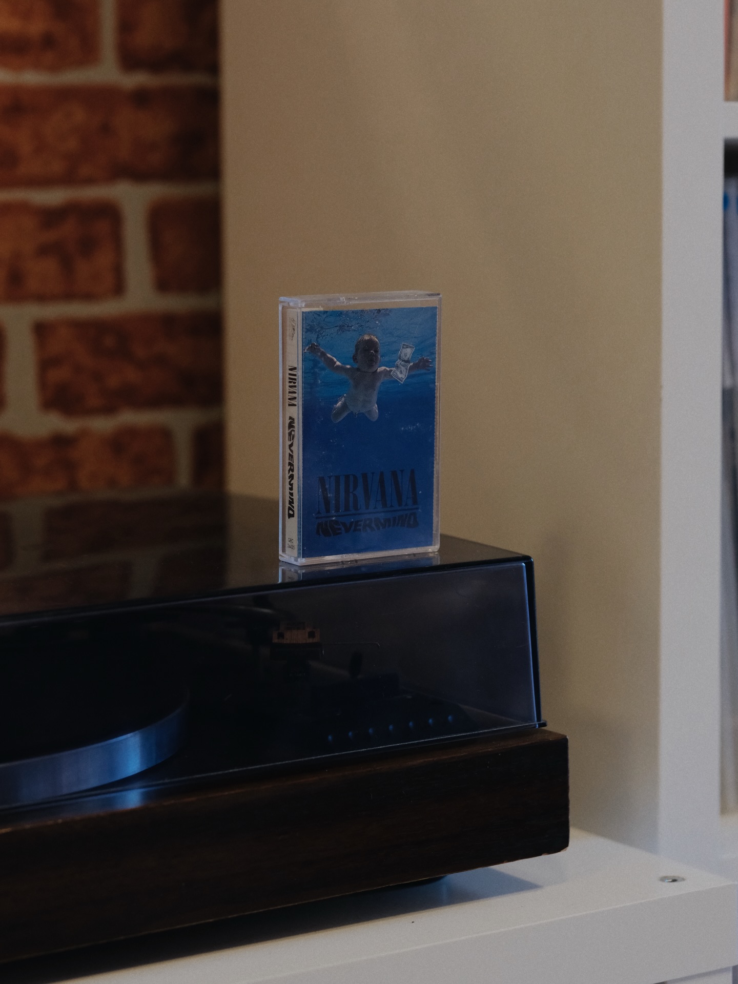 Nirvana Nevermind cassette case placed on a retro turntable in a cozy room setting