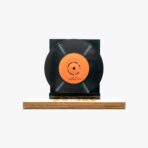 Black vinyl record mounted on a dark stand atop a light wooden base with an orange center label that reads 'HER ŞEY TRABZON İÇİN'.