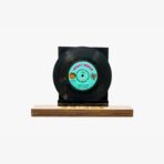 2301450005D | 3345 Records Black vinyl record mounted on a wooden display stand against a white background.