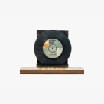 Black vinyl record mounted on a wooden display stand, shown upright as a decorative piece.