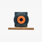 Black vinyl record on a wooden platform with an orange label, set against a white background.