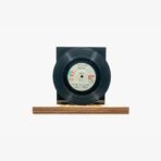Black vinyl record mounted on a wooden display stand against a white background.”