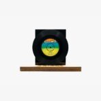 Black vinyl record mounted on a square black display block set on a wooden base.