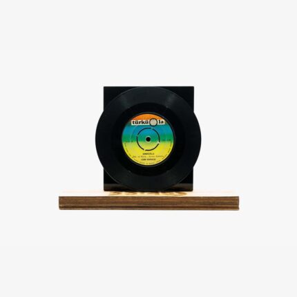 Black vinyl record mounted on a square black display block set on a wooden base.