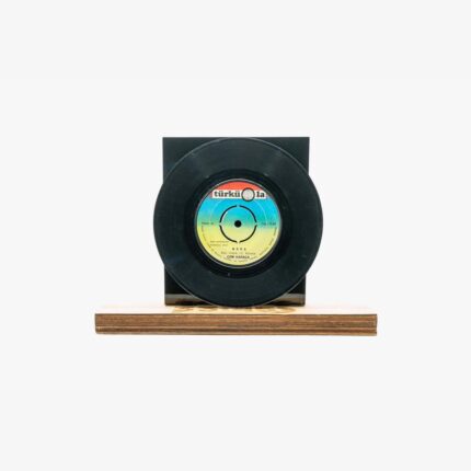Decorative sculpture of a black vinyl record mounted on a wooden block with a dark backing.