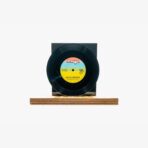 Black vinyl record on a wooden display stand with a blue-yellow label at center, Turkish music record artwork visible.