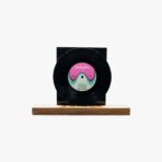 A black vinyl record mounted on a wooden base with a pink-and-teal label reading 'tiirkofon' in the center.