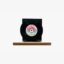 Black vinyl record mounted on a wooden platform, label facing outward, against a white background on display.