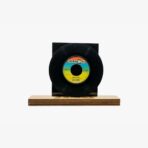 2301450060B | 3345 Records Black vinyl record mounted on a small wooden display base, with a colorful label at the center.