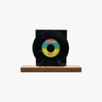 2301450060C | 3345 Records A black vinyl record mounted on a square black display block resting on a wooden base.