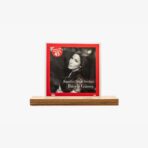 Framed black-and-white album cover with a red border on a wooden display pedestal, featuring a portrait of Burcu Güneş and Turkish text.