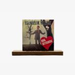 Album cover for Yalnızlık Yarası by Erol Büyükburç, featuring a man in a suit beside a large red heart on a muted backdrop on a wooden stand
