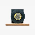 Black vinyl record mounted on a wooden display base against a white background.
