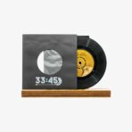 Vinyl record partially pulled from a dark sleeve with '33:45' text, resting on a wooden display base