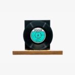 Vintage black vinyl record mounted on a wooden display base with a turquoise label at center label reads Yonca (classic record).
