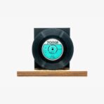 Black vinyl record mounted on a wooden base with a turquoise Yonca label at center, displayed against a light background.